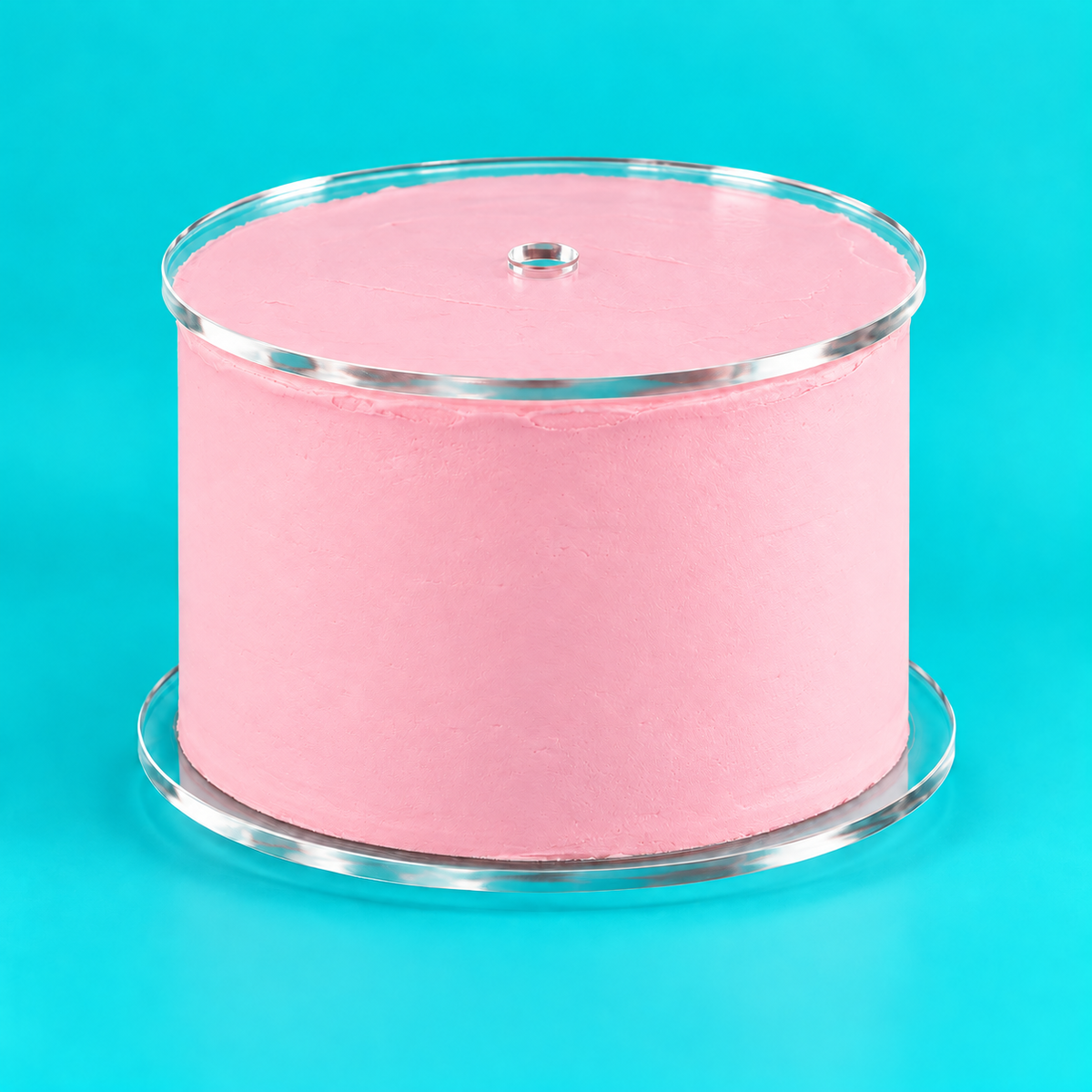 Pastel pink cake sitting on clear round acrylic cake disks