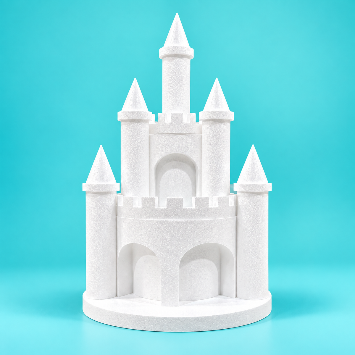 White foam princess castle cake dummy with five pointed towers, two round levels, arched openings, and a circular base on a turquoise background