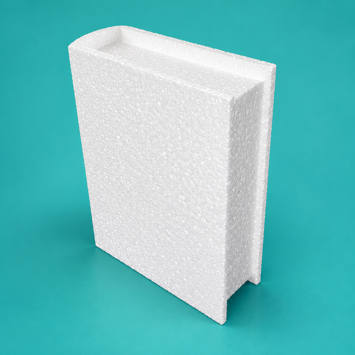Closed book foam cake dummy lying flat showing raised cover edge and recessed page block on teal background