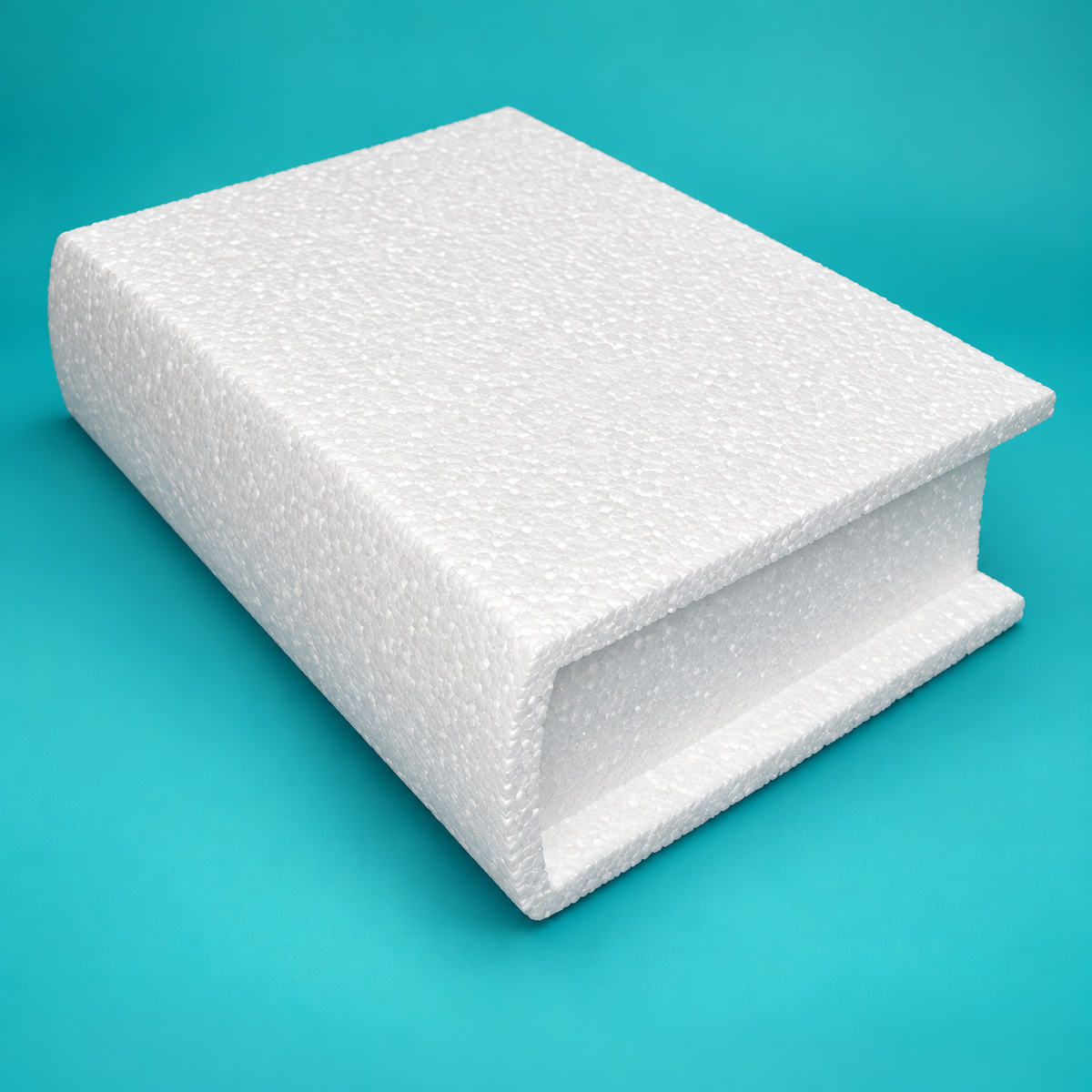 White foam closed book cake dummy standing upright with curved spine and recessed pages on teal background