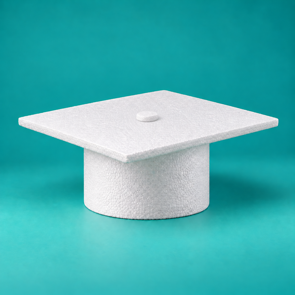 White graduation cap foam cake dummy with flat square mortarboard top, center button and round base, angled view