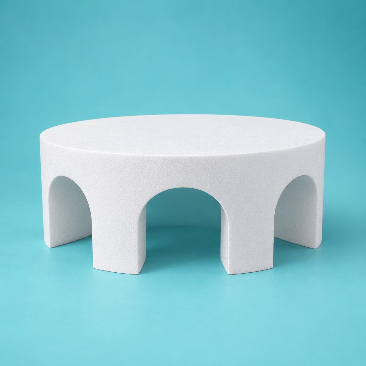 Round foam cake dummy with three evenly spaced arch cutouts through the tier, smooth white finish